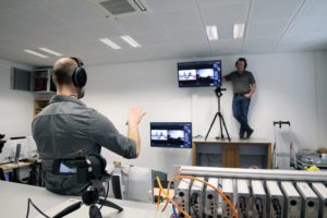 Trainer Hendrik Müller standing on the cabinet behind the camera while Christopher Gottwald teaches the participants the content in front of the camera.