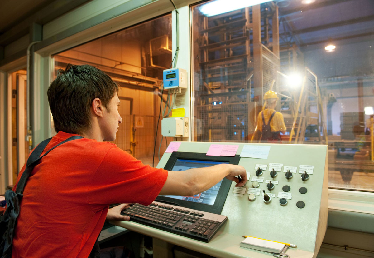 Man in red shirt working in an industrial control room